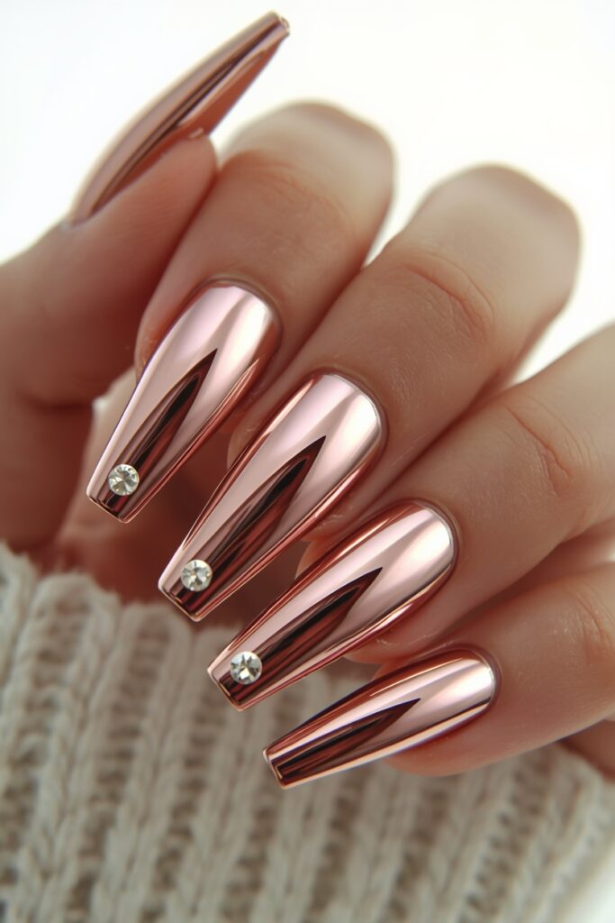 Rose gold chrome prom nails with rhinestone detail on coffin shape