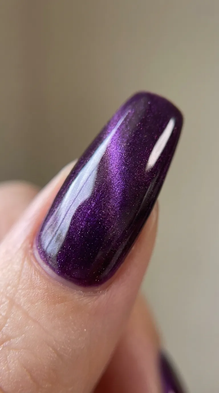 Close-up of purple cat eye almond nails with light catching the magnetic shimmer
