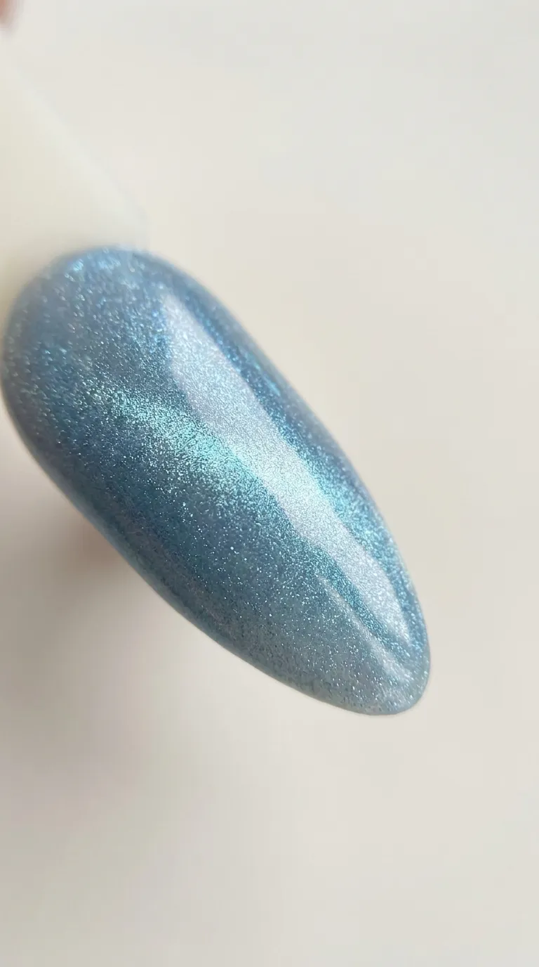 Close-up of blue cat eye nails with directional light catching the icy magnetic band