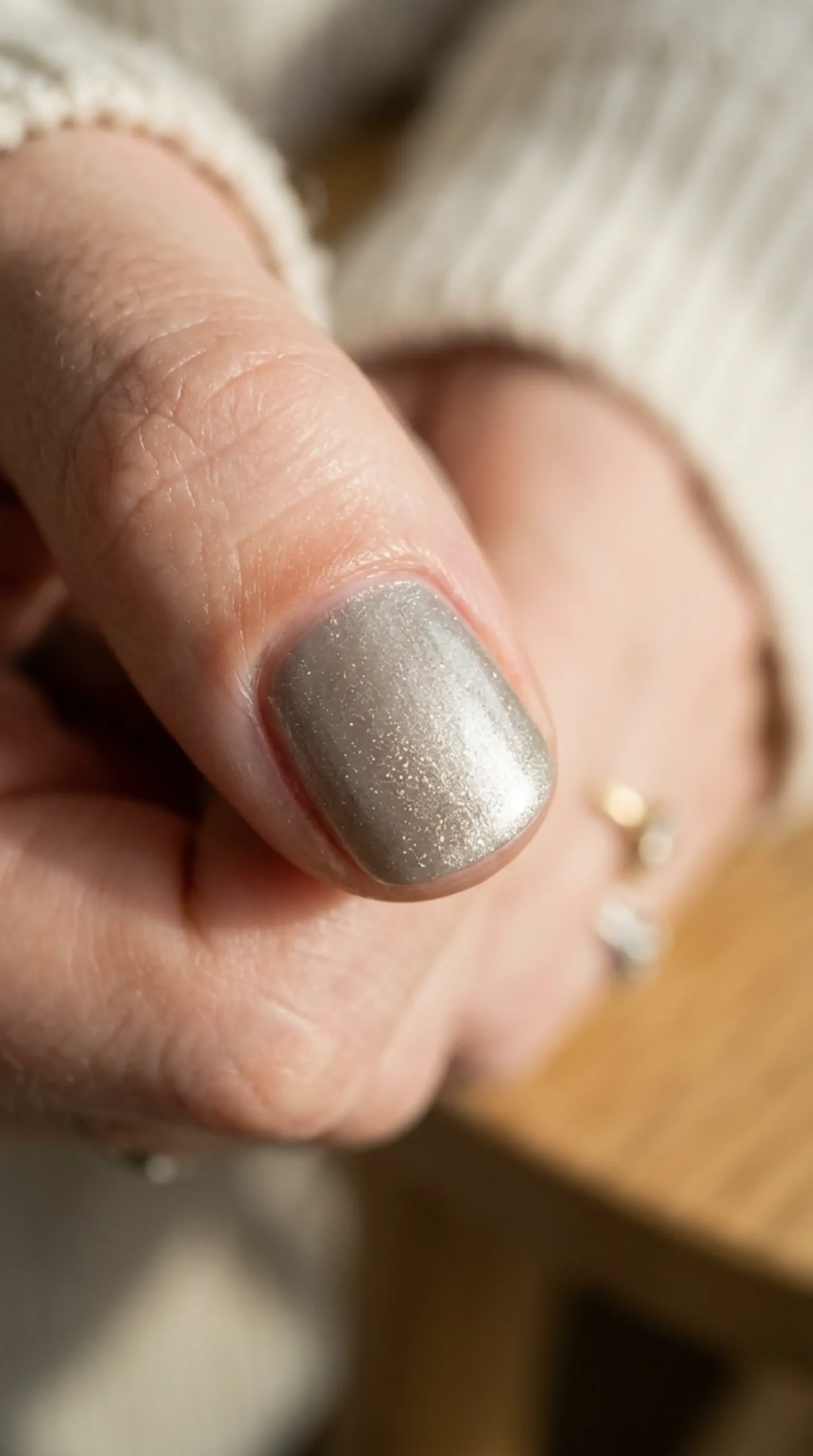 Macro of muted champagne silver nail polish shimmer in directional light