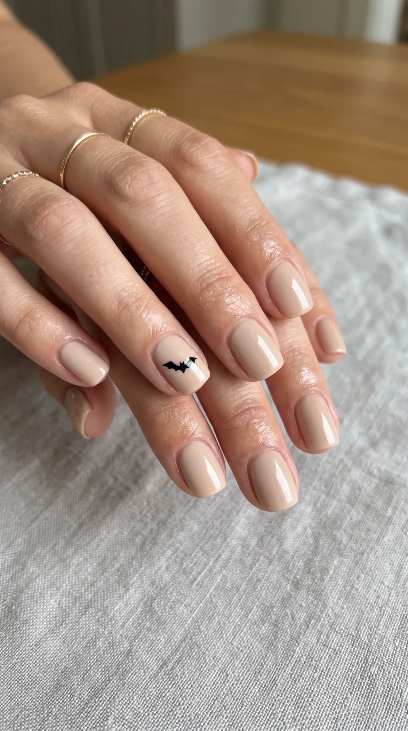 nude bat nails with a single minimalist black bat accent