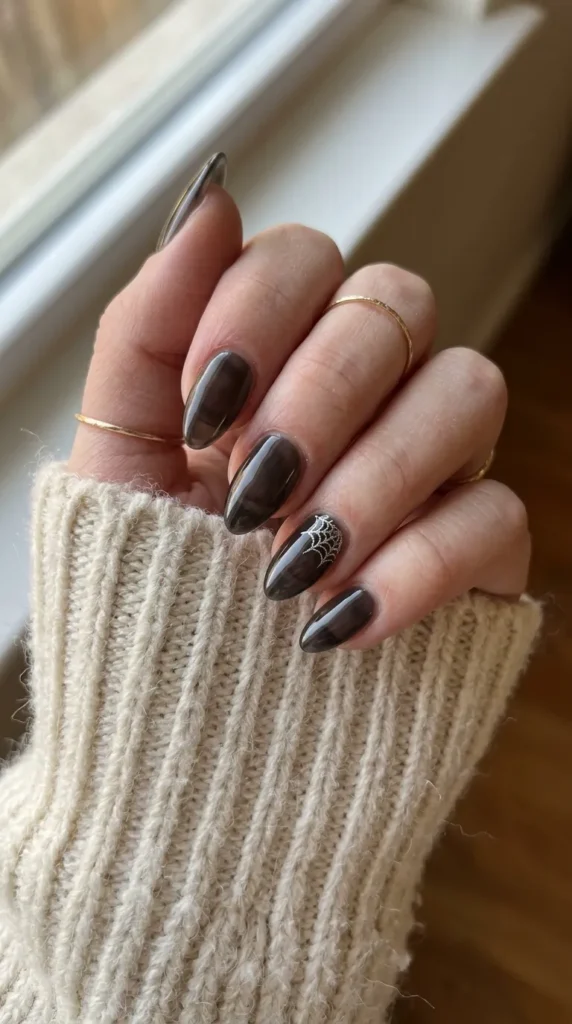 Sheer black jelly almond nails with a tiny silver web in one corner