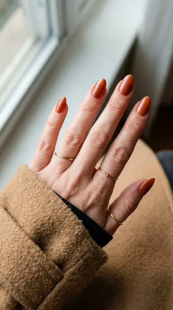 Burnt orange glossy almond nails with a soft glazed finish