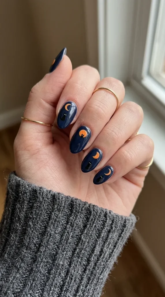 almond halloween nails: dark nail with an orange moon and a black cat silhouette