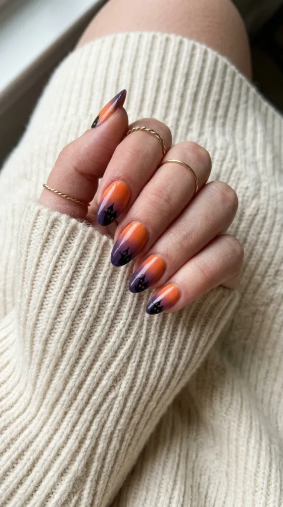Orange to purple gradient almond nails with a black haunted house silhouette