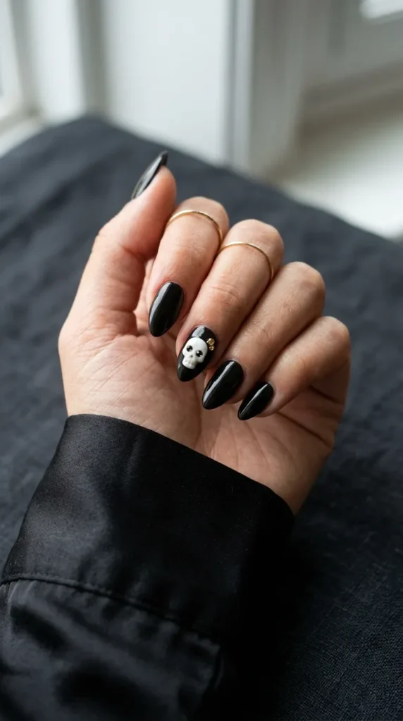 One nail with a small white skull with black crystal eyes and a gold stone