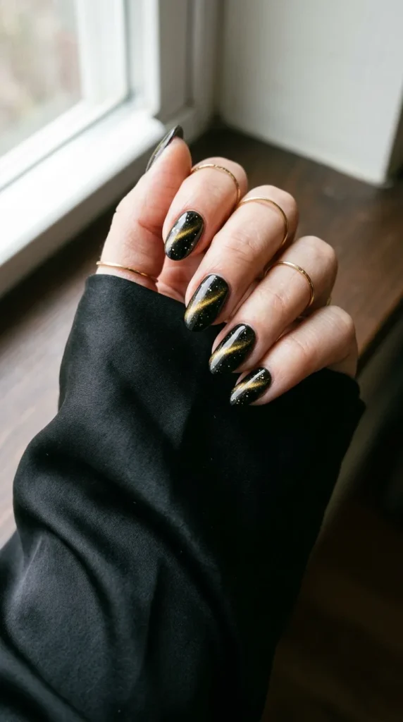 Black cat eye nails with a gold magnetic line and gold flecks