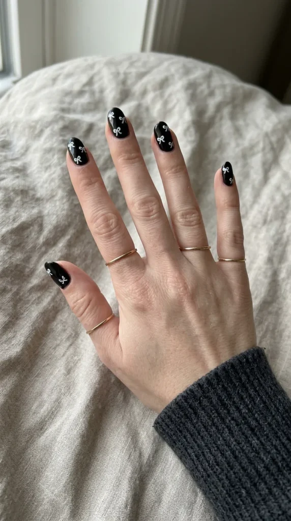 Glossy black nails with small white bows scattered across them