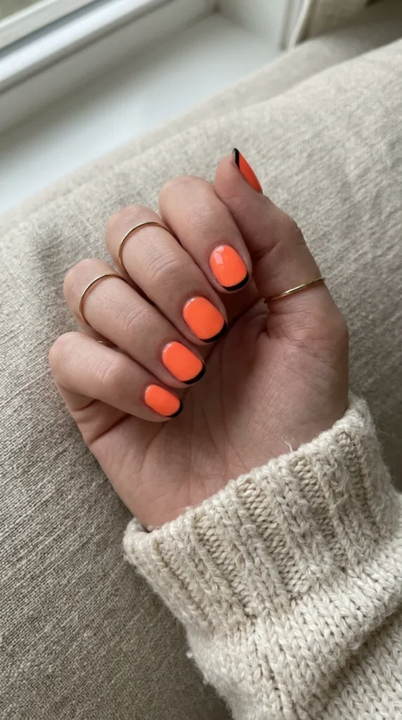 orange halloween nails: short nails in neon orange with crisp black French tips