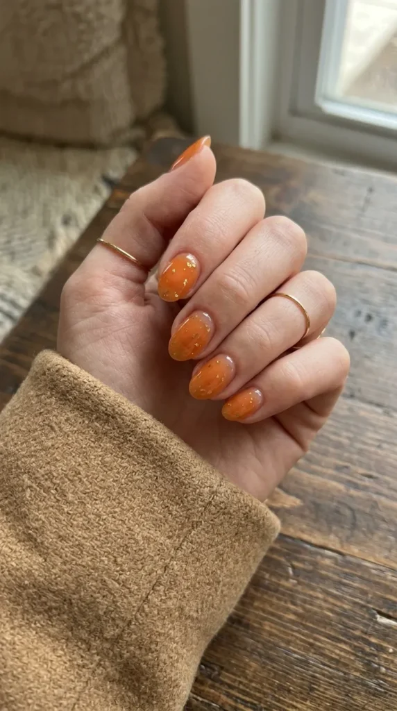 Translucent orange jelly nails with small gold flecks