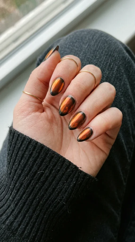 Black nails with a glowing orange chrome finish