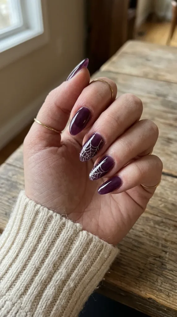 purple halloween nails: deep grape jelly nails with a thin silver spiderweb
