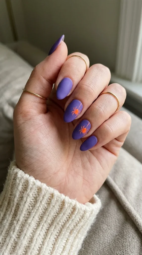 Matte violet nails with small neon orange spiders