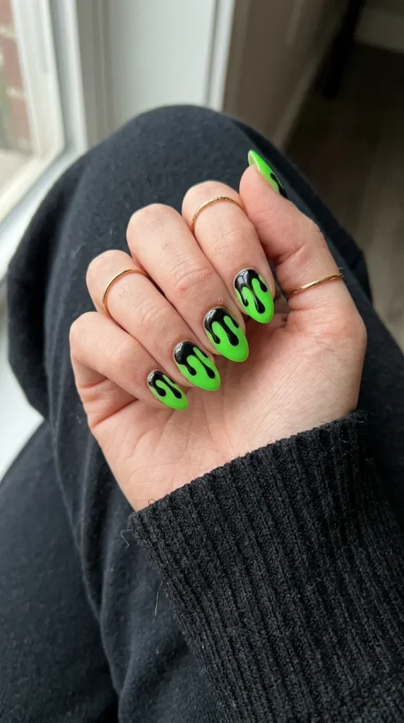 green halloween nails: neon green nails with black drips from the cuticle