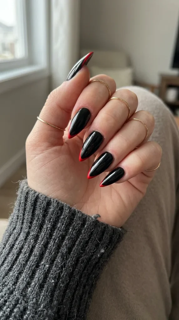 stiletto halloween nails: long glossy black stiletto nails with thin red tips