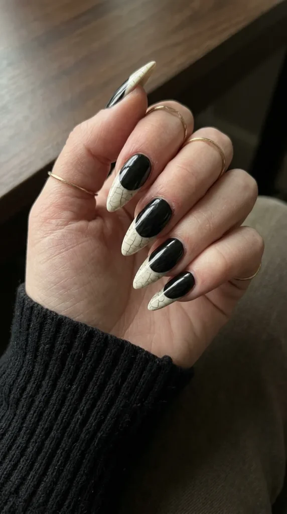 Black stiletto nails with off-white bone-colored tips and fine cracks
