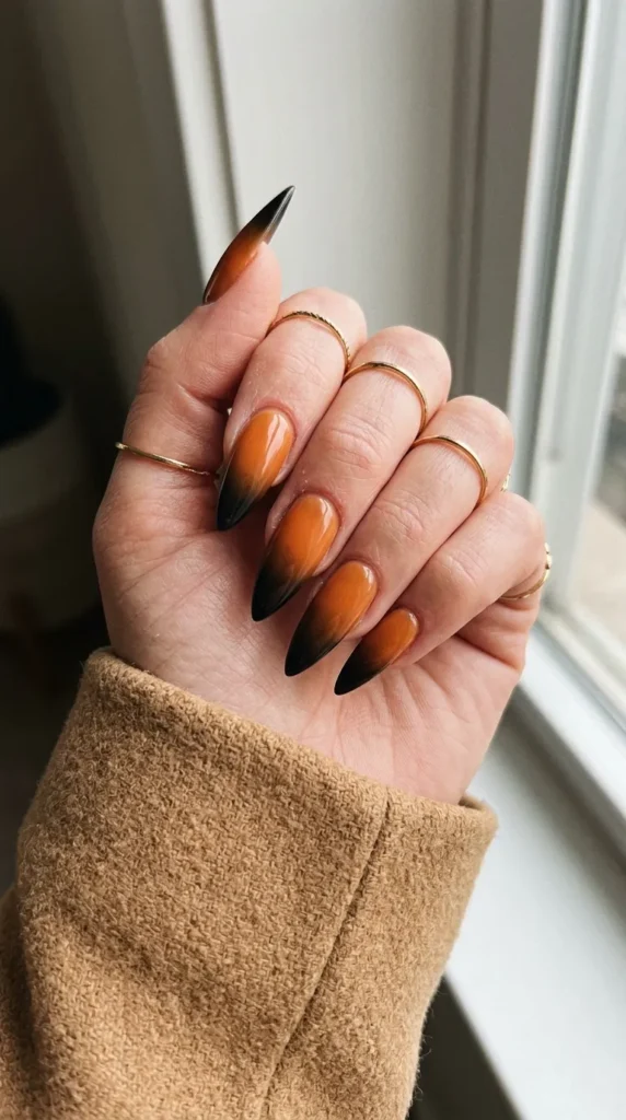 Stiletto nails with an orange to black gradient