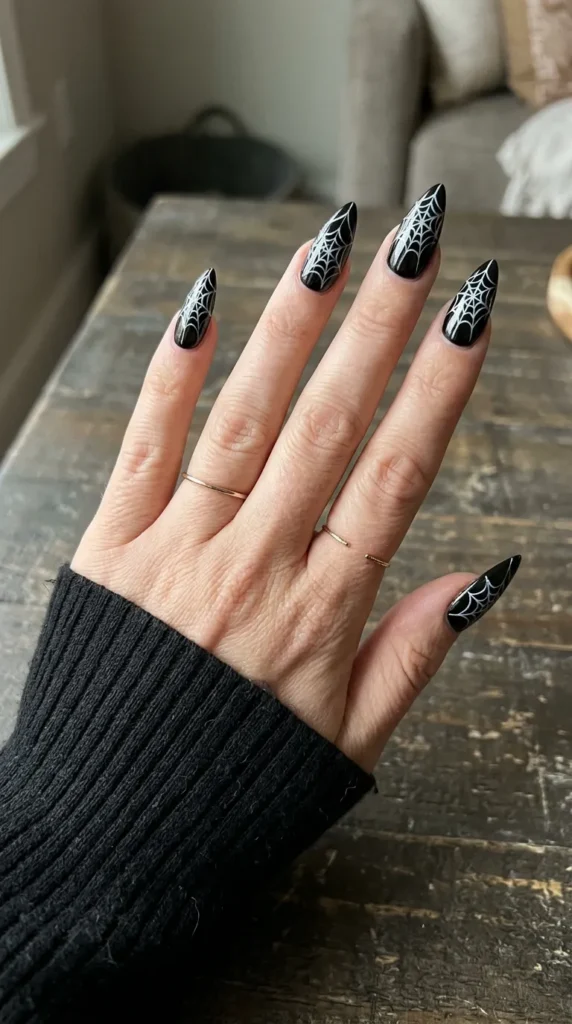 Black stiletto nails with a white spiderweb spreading across each nail