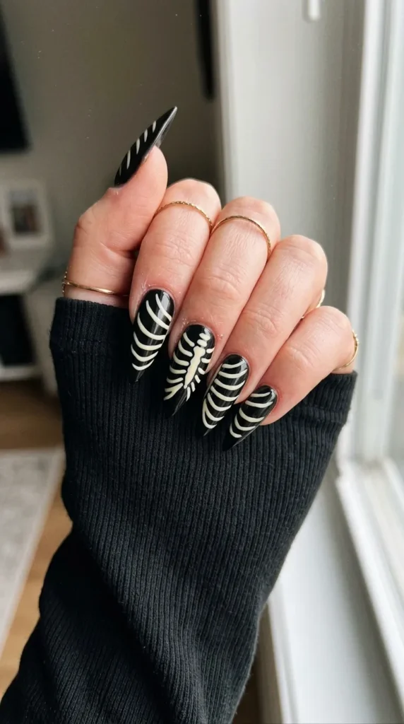 stiletto halloween nails: black stiletto nails with white rib lines that connect across fingers