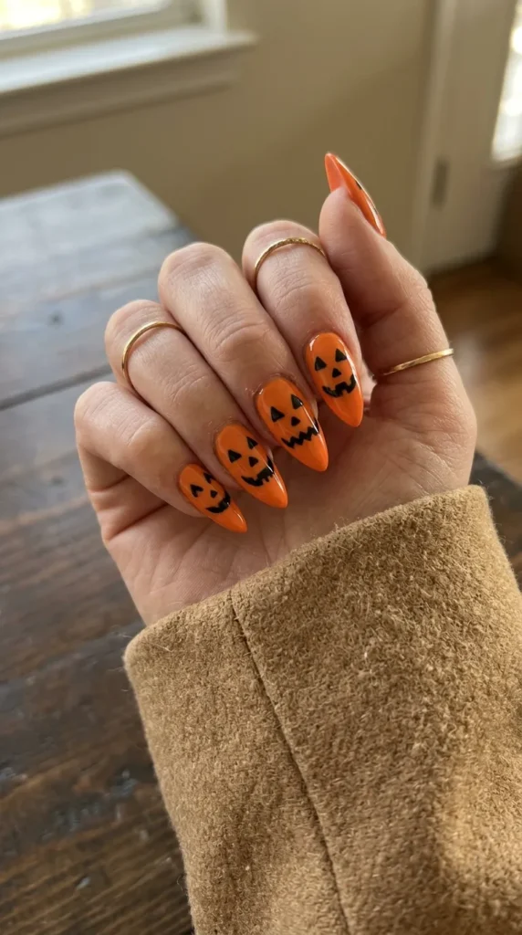 Orange stiletto nails with black carved jack-o-lantern faces