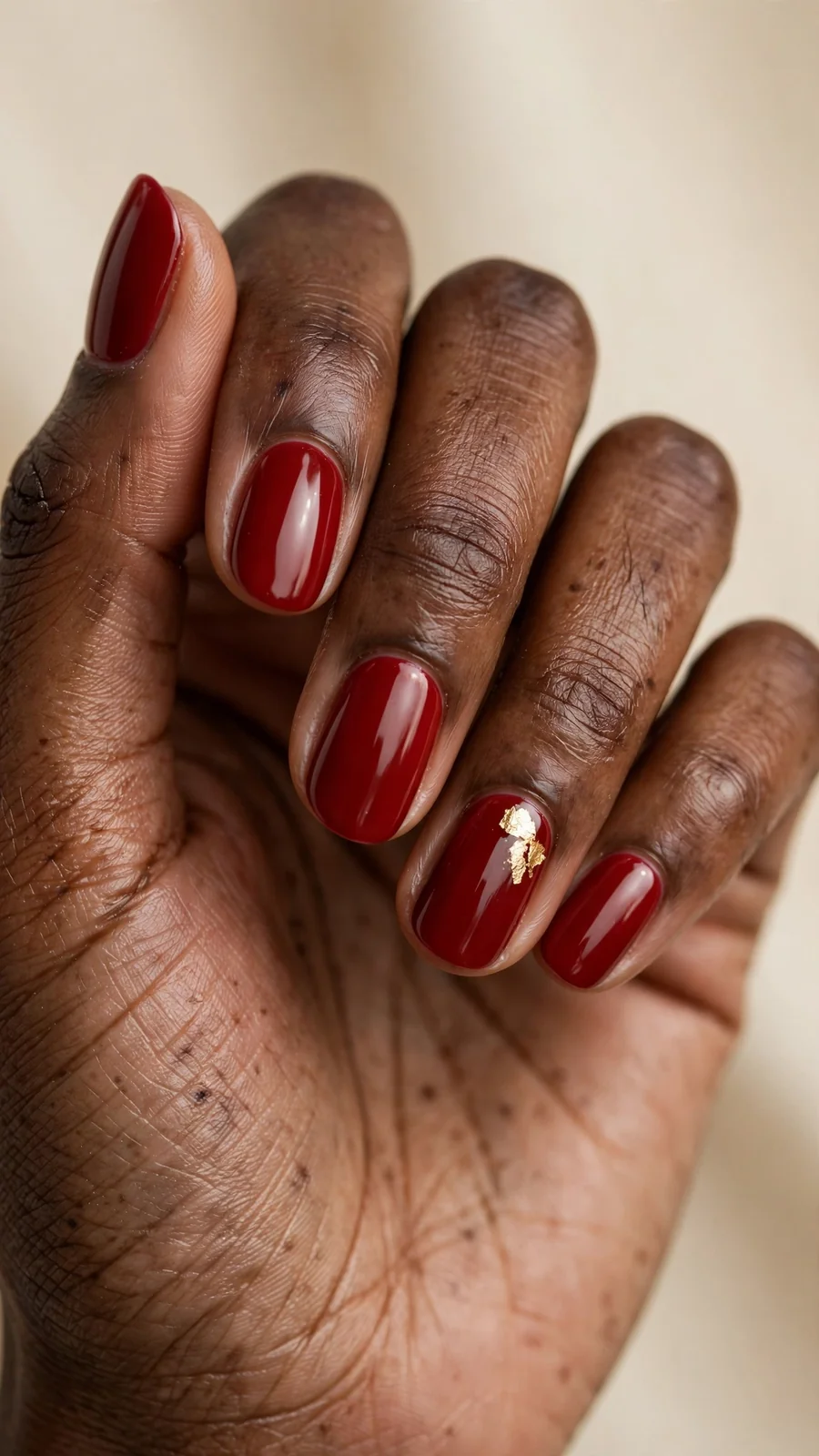 Thanksgiving nail designs: glossy apple-red nails with gold leaf accent