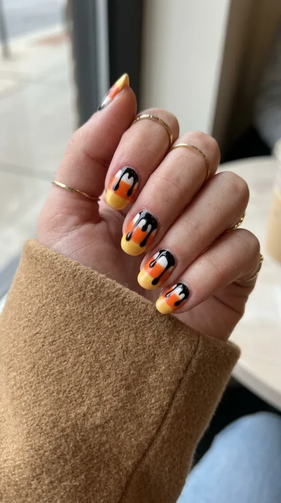 Candy corn striped nails with uneven bands and black drips