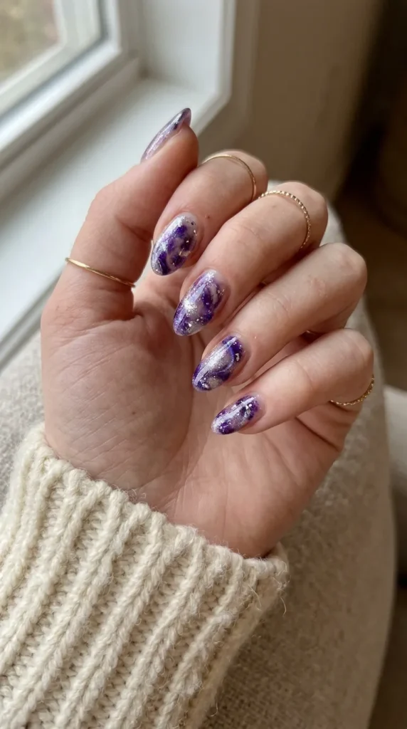 Clear nail with swirling purple and silver glitter like a crystal ball