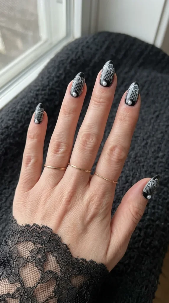 Black nails with white lace pattern and one small pearl